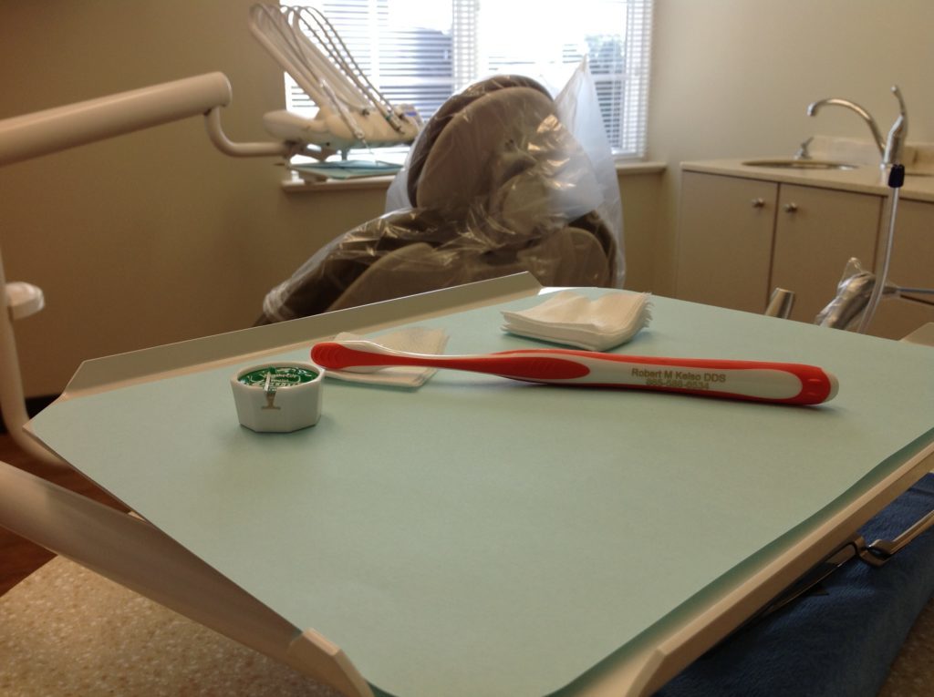 Image of a tooth brush and a cup of tooth polish used for teeth cleaning which is one of the general dentistry items at Robert M Kelso DDS.